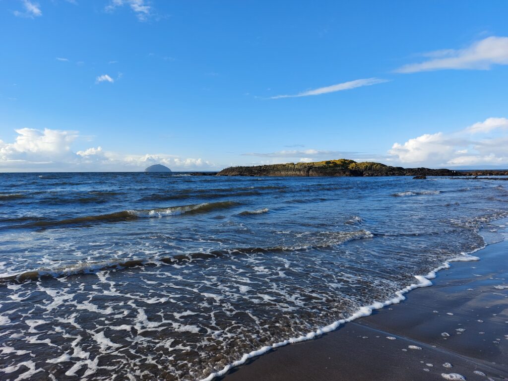 Beach and rocky island Horse Rock, with the island Ailsa Craig in the background