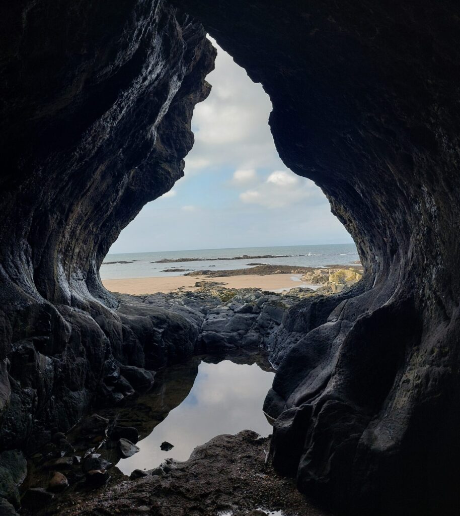 A sandy shore seen through a sea cave